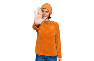 Young hispanic woman wearing casual clothes and wool cap doing stop sing with palm of the hand....