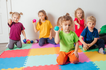 Lovely toddler boy playing with small balls and plastic basket