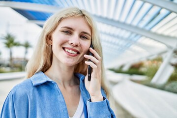 Young blonde woman outdoors on a sunny day speaking on the phone
