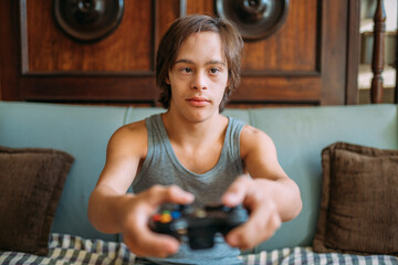 Young latin man with down syndrome playing video games at home.