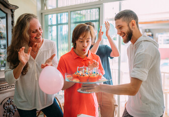 Young latino downs syndrome man celebrating birthday at home with cake