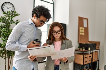 Two business workers with serious expression reading paperwork working at the office.