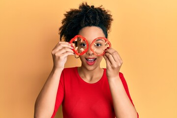 Young african american girl holding red pepper as a glasses celebrating crazy and amazed for success with open eyes screaming excited.