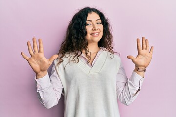 Young brunette woman with curly hair wearing casual clothes showing and pointing up with fingers number ten while smiling confident and happy.