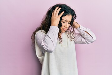 Young brunette woman with curly hair wearing casual clothes suffering from headache desperate and stressed because pain and migraine. hands on head.