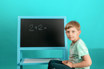 The boy solves the math equation 2 + 2 written on the blackboard. The child does not know the answer to simple examples.