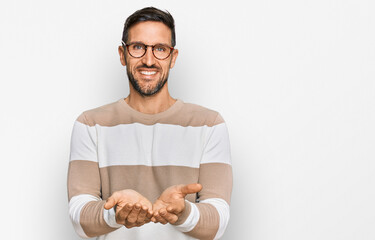 Handsome man with beard wearing casual clothes and glasses smiling with hands palms together...