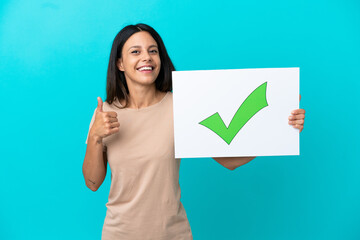 Young woman over isolated background holding a placard with text Green check mark icon with thumb up