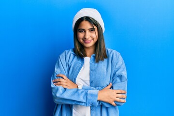 Young latin woman wearing cute wool cap happy face smiling with crossed arms looking at the camera. positive person.