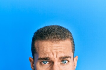 Young caucasian man showing head and half face in shock face, looking skeptical and sarcastic, surprised with open mouth