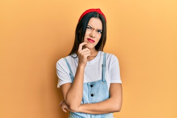 Young hispanic girl wearing casual clothes thinking concentrated about doubt with finger on chin and looking up wondering