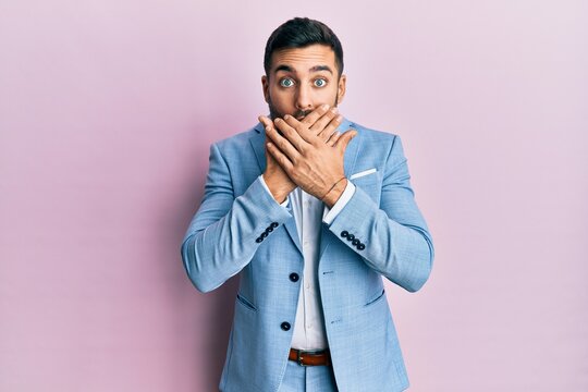 Young hispanic businessman wearing business jacket shocked covering mouth with hands for mistake. secret concept.