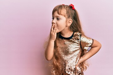 Little caucasian girl kid wearing festive sequins dress bored yawning tired covering mouth with...