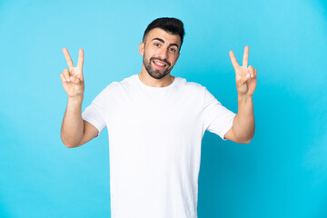 Naklejka premium Caucasian man over isolated blue background showing victory sign with both hands