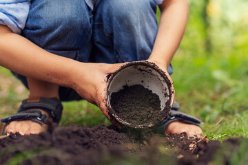 Close-up of a boy digging with a bucket in the garden for planting a plant