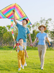 Happy family of three flying kites in the park
