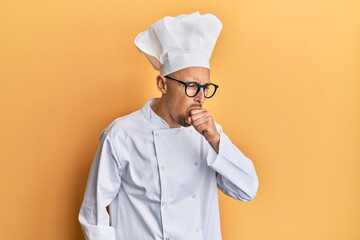 Bald man with beard wearing professional cook uniform feeling unwell and coughing as symptom for cold or bronchitis. health care concept.