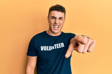 Hispanic young man wearing volunteer t shirt pointing displeased and frustrated to the camera, angry and furious with you