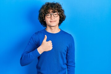 Handsome young man wearing casual clothes and glasses doing happy thumbs up gesture with hand....
