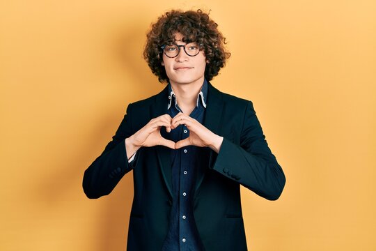 Handsome young man wearing business jacket and glasses smiling in love showing heart symbol and shape with hands. romantic concept.