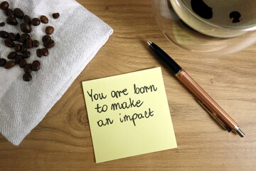 You are born to make an impact text handwritten on sticky note with coffee and pen