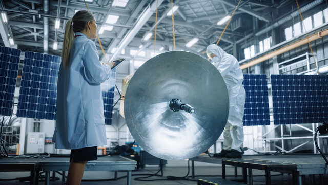 Female Engineer Uses Digital Tablet Computer while Working on Satellite Construction. Aerospace Agency: Scientist Overseeing Building, Assembly and Manufacturing of Spacecraft for Space Mission