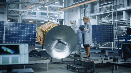 Female Chief Engineer talk to Technician while he is Working on Satellite Construction. Aerospace...