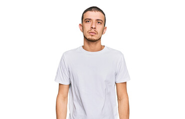 Hispanic young man wearing casual white t shirt relaxed with serious expression on face. simple and natural looking at the camera.