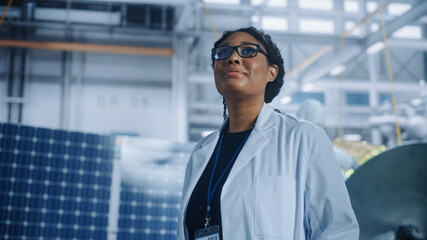 Brilliant Female Engineer Looking Around in Wonder at the Aerospace Satellite Manufacturing...
