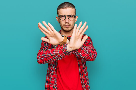 Hispanic young man wearing casual clothes rejection expression crossing arms doing negative sign, angry face