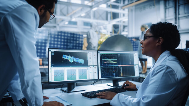 Managing Engineer and Chief Technician Working on Satellite Construction, Talk, Use Computer. Aerospace Agency Manufacturing Facility: Scientists Assemble Spacecraft for Space Exploration Mission