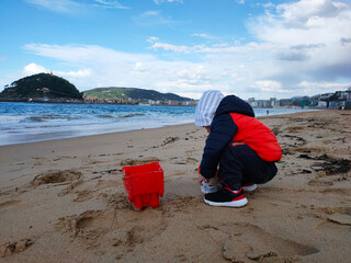 child playing with sand on the beach out of season