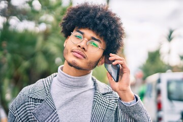 Young african american businessman with serious expression talking on the smartphone at the city.