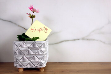 Word simplify handwritten on sticky note with blossoming flower
