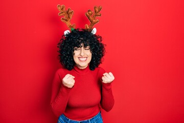 Young middle east woman wearing cute christmas reindeer horns excited for success with arms raised and eyes closed celebrating victory smiling. winner concept.