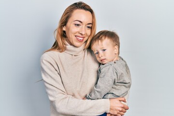 Young caucasian woman holding and hugging her son with love. Family of two bonding together. Mother holding infant toddler