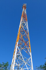 Red and white cell phone mast, radio communication station against bright blue sky, Alter do Chao,...