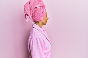 Middle age hispanic woman wearing shower towel cap and bathrobe looking to side, relax profile pose with natural face with confident smile.