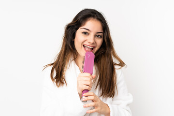 Young caucasian woman isolated on white background with hair comb and singing
