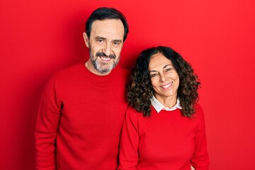 Middle age couple of hispanic woman and man hugging and standing together with a happy and cool smile on face. lucky person.