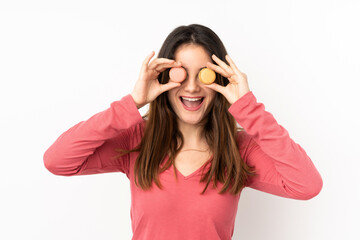Young caucasian woman isolated on pink background holding colorful French macarons with surprised expression
