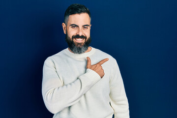 Young hispanic man wearing casual clothes cheerful with a smile of face pointing with hand and finger up to the side with happy and natural expression on face