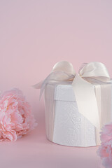 Gift box with ribbon and beautiful pion flower on light pink background.Space for text.Happy birthday, valentine's day, weddings card concept.
