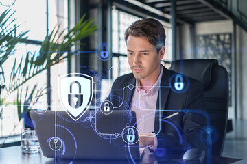 Handsome businessman in suit at workplace working with laptop to defend customer cyber security. Concept of clients information protection and brainstorm. Padlock hologram over office background. - Powered by Adobe