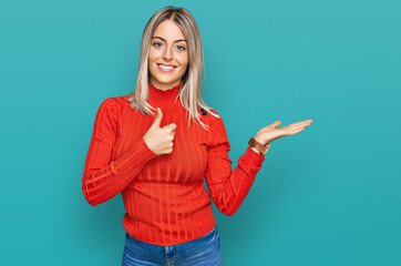 Beautiful blonde woman wearing casual clothes showing palm hand and doing ok gesture with thumbs up, smiling happy and cheerful