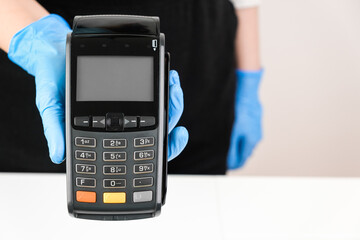 Close up woman in rubber gloves holding a pos terminal. Contactless payment during pandemic using nfc technology