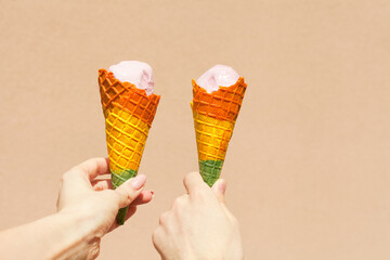 rainbow ice cream cone - two hands holdling ice cream cones in rainbow colors at hot summer day