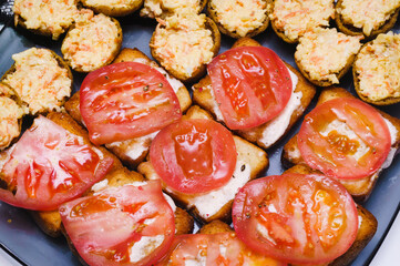 baked brown buns with cream cheese and tomatoes on top, next to a cheese snack