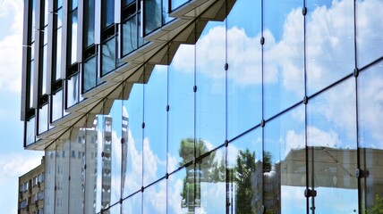 Fototapeta na wymiar Glass and aluminum facade of a modern office building. View of futuristic architecture. Office building with cloud reflection on windows