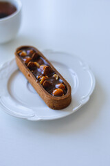 chocolate cake with nuts and caramel on white plate, copy space